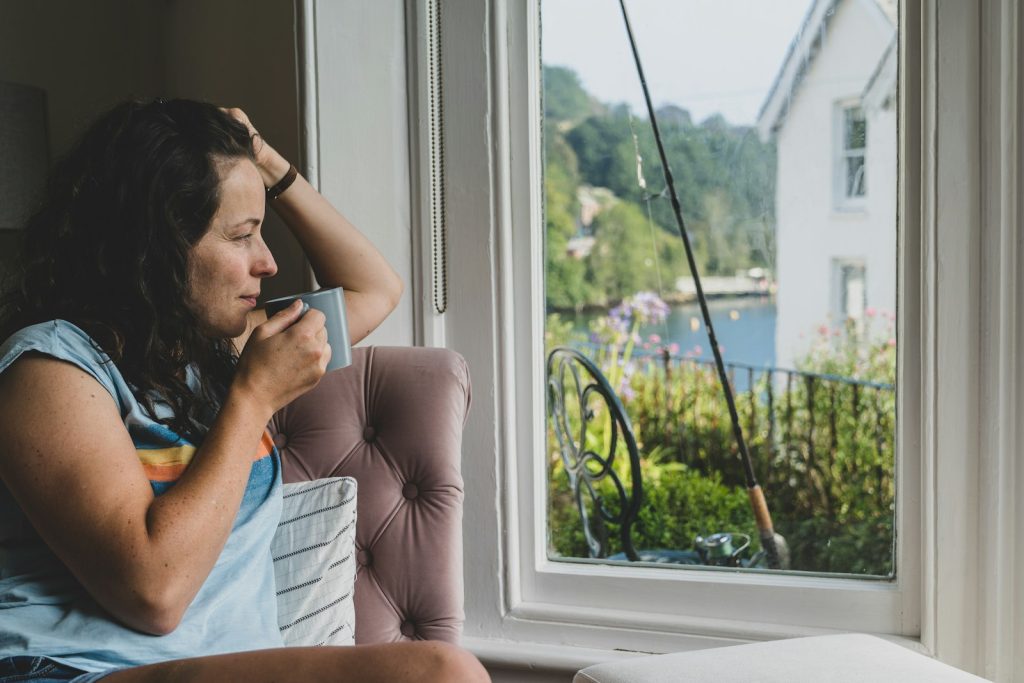 a woman sitting in a chair looking out a window, peaceful happy woman