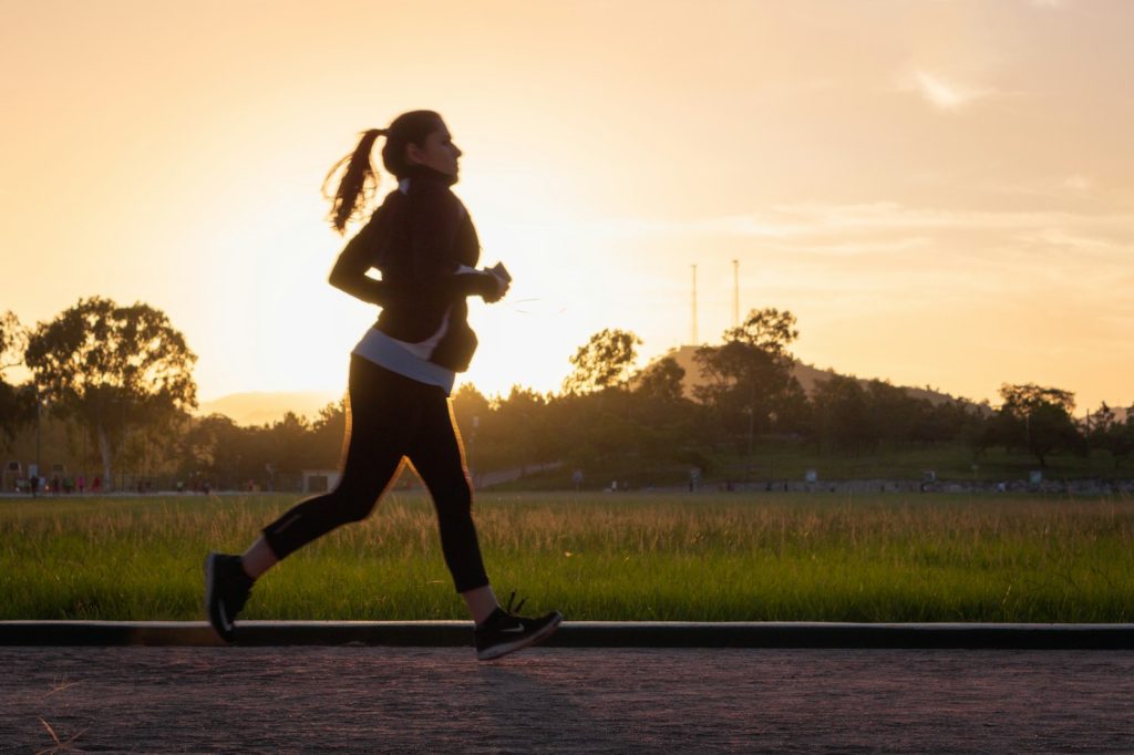 woman in black sports bra and black pants running on water during sunset, blog about how to stop thinking about something