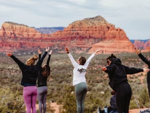 group of women practicing yoga outdoors in Sedona red rock landscape, yoga retreat. 