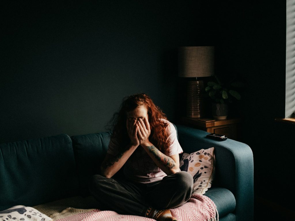 woman in black and white floral shirt sitting on black couch looking frustrated. blog about how to stop being stuck when letting go