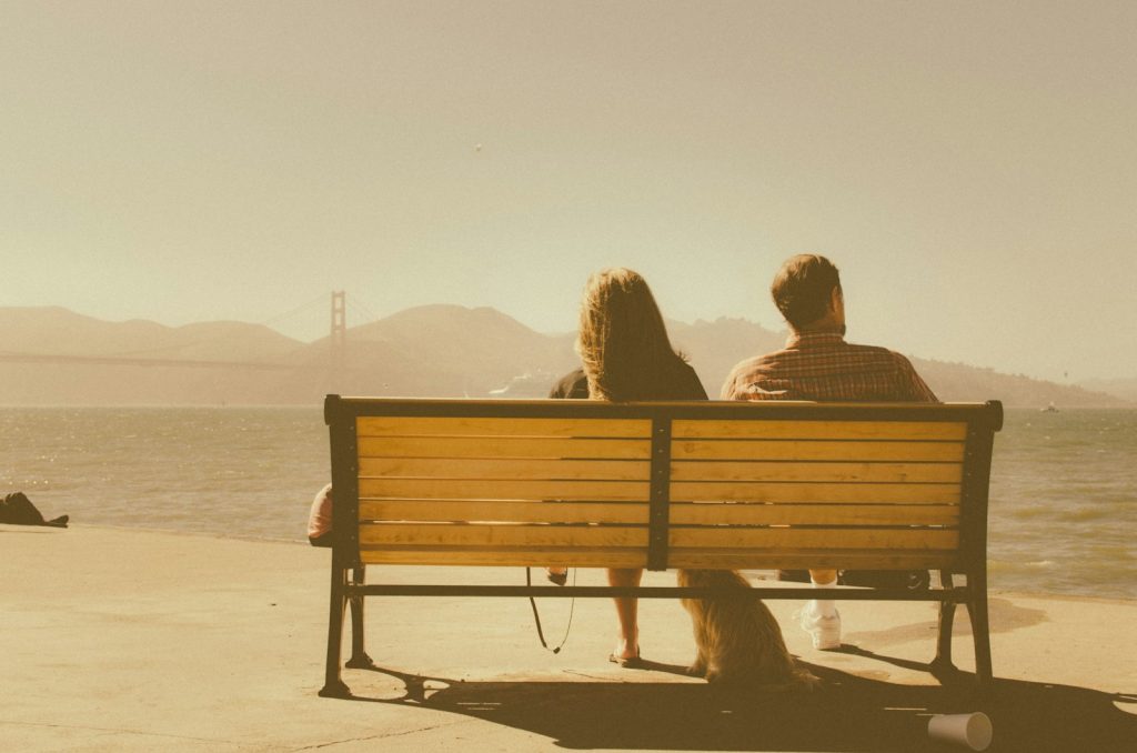 man and woman sitting on bench beside body of water. blog post about letting go of someone you love