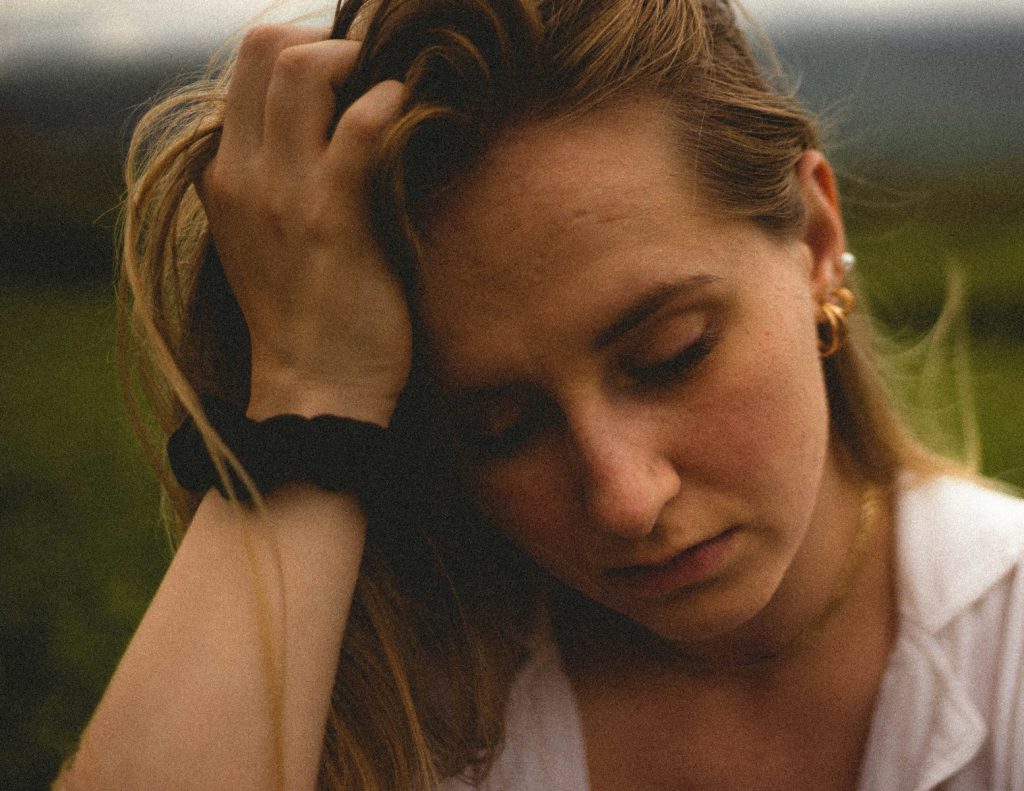 woman in white tank top looks sad
