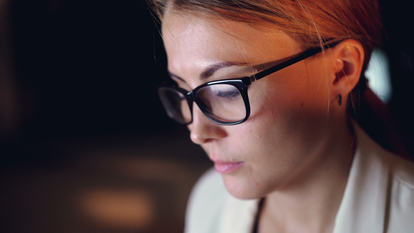 Woman wearing glasses looking intently at screen, considering ai therapy
