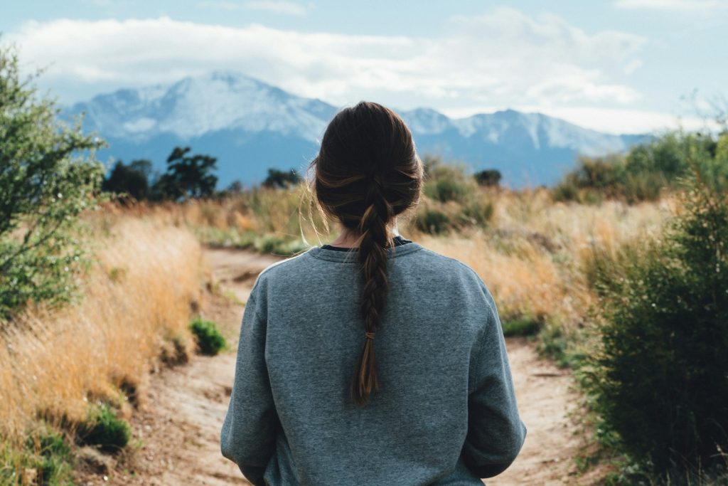 woman walking along pathway during daytime, moving forward, healing, progress