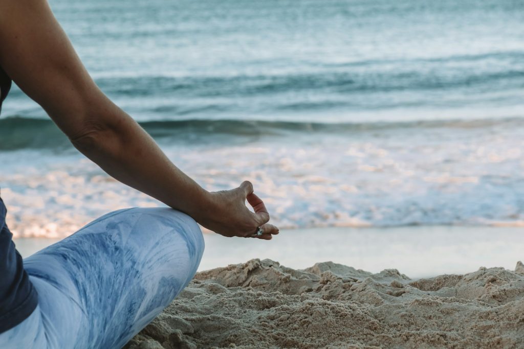 person in blue shorts sitting on beach shore during daytime, meditating practicing radical acceptance