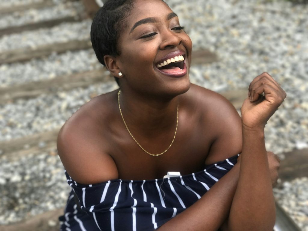 candid shot of woman wearing black and white striped off-shoulder top, she's smiling and having fun