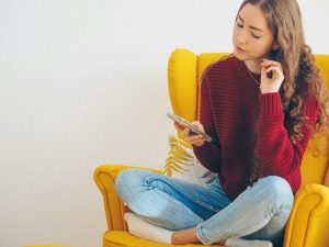 teen attachment styles - Blair Nicole | Mental Health, Relationships, Travel woman in red sweater and blue denim jeans sitting on yellow sofa chair blog post about teen attachment styles
